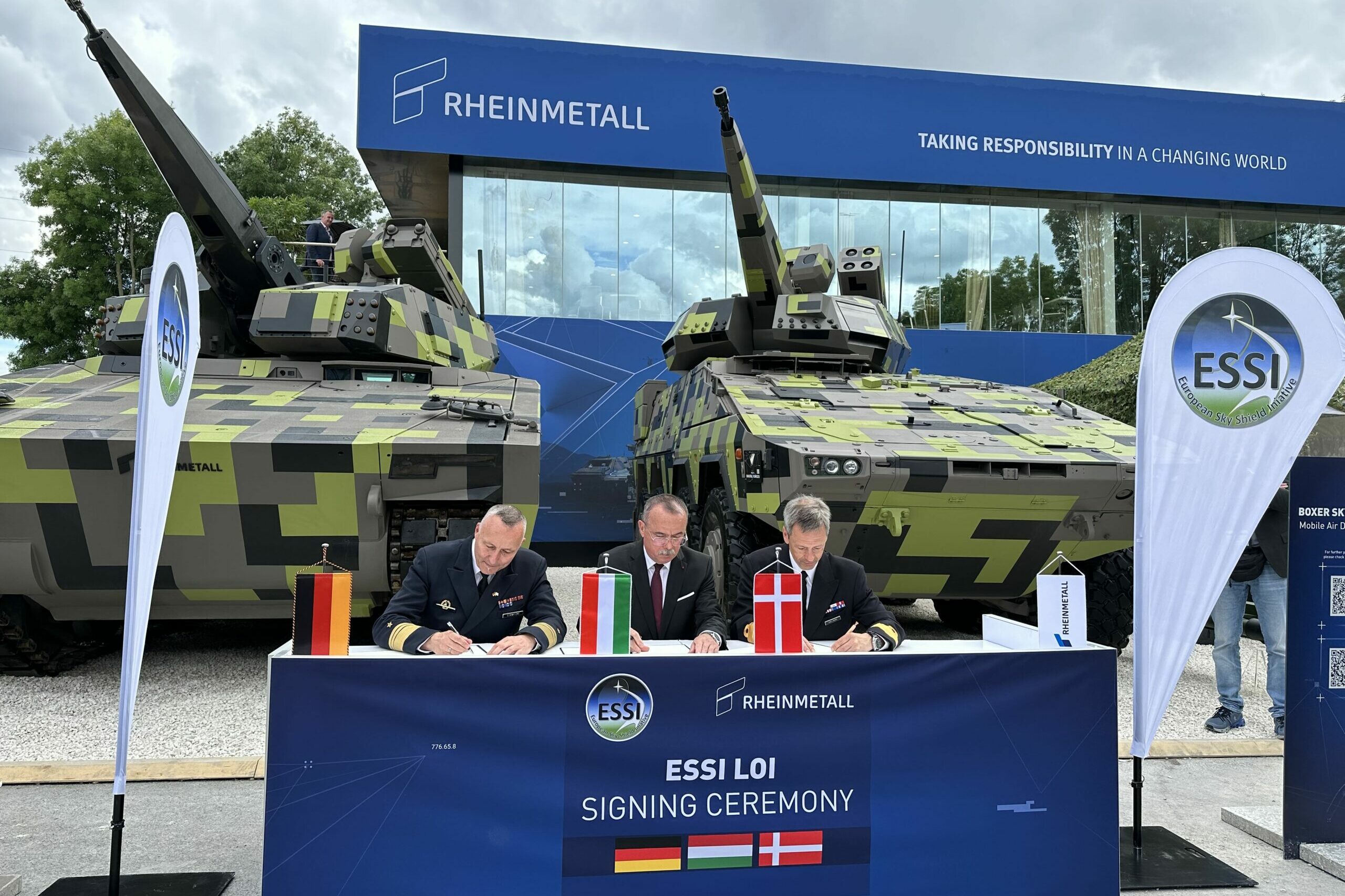 Beschaffung Skyranger: Vizeadmiral Carsten Stawitzki, Abteilungsleiter Rüstung im BMVg (Deutschland), General a.D. Laszlo Tömböl, Nationaler Rüstungsdirektor (Ungarn) und Flottillenadmiral Claus Lundholm Andersen, Stv. Nationaler Rüstungsdirektor (Dänemark), bei der Unterzeichnung des LoI. Im Hintergrund ein Skyranger auf Lynx und einer auf Boxer (v.l.n.r.).